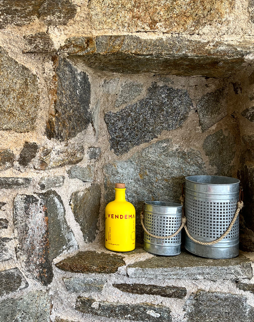 Stone wall with Vendema Organic Extra Virgin Olive Oil Bottle.