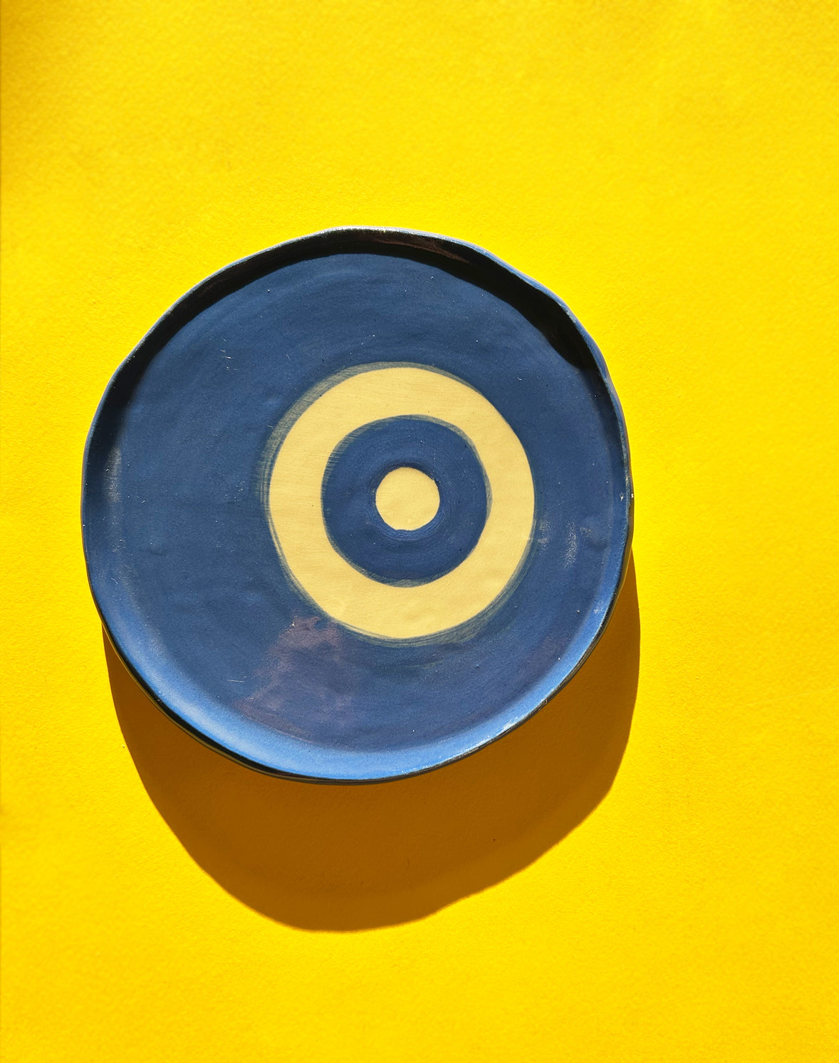 View from above of blue ceramic plate with painted evil eye.