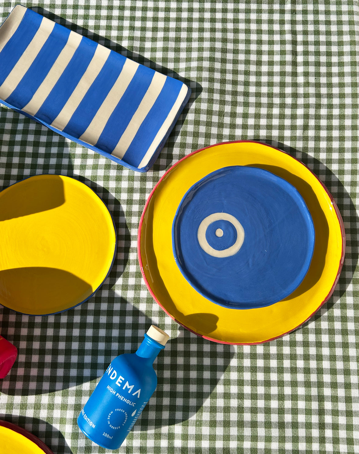 View from above of colourful ceramic plates and platters and Vendema Olive Oil Bottle.