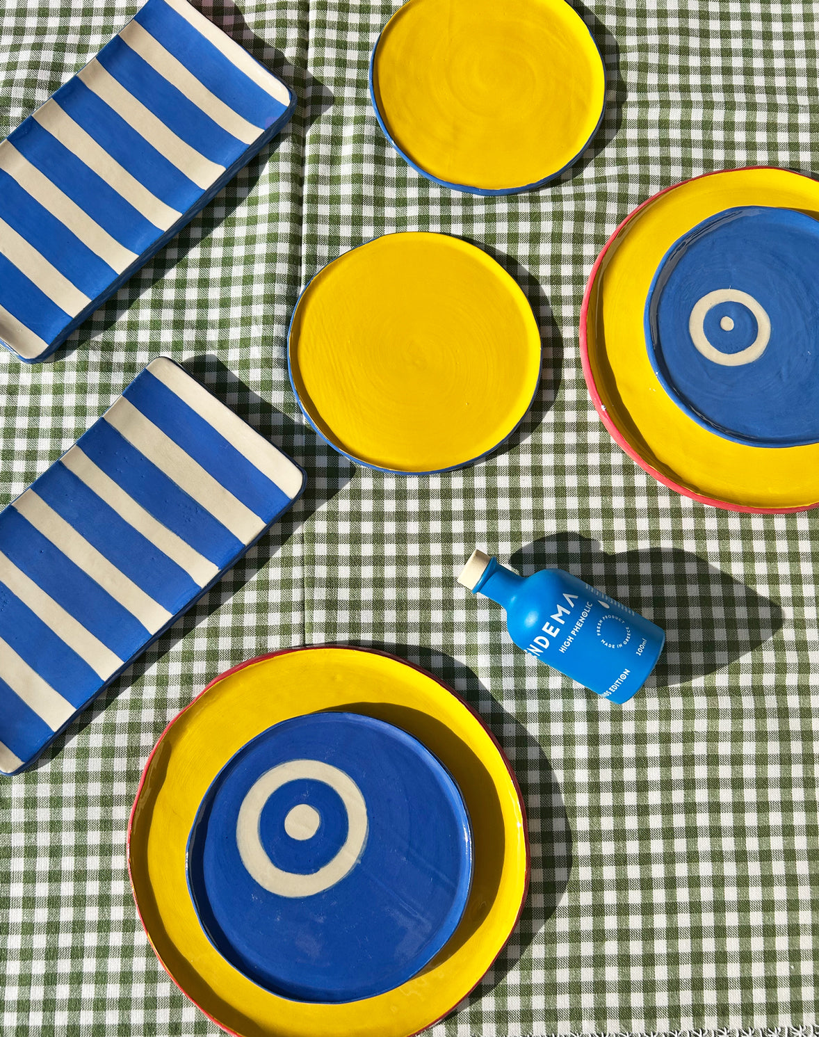 View from above of colourful ceramic plates and platters and Vendema Olive Oil Bottle.