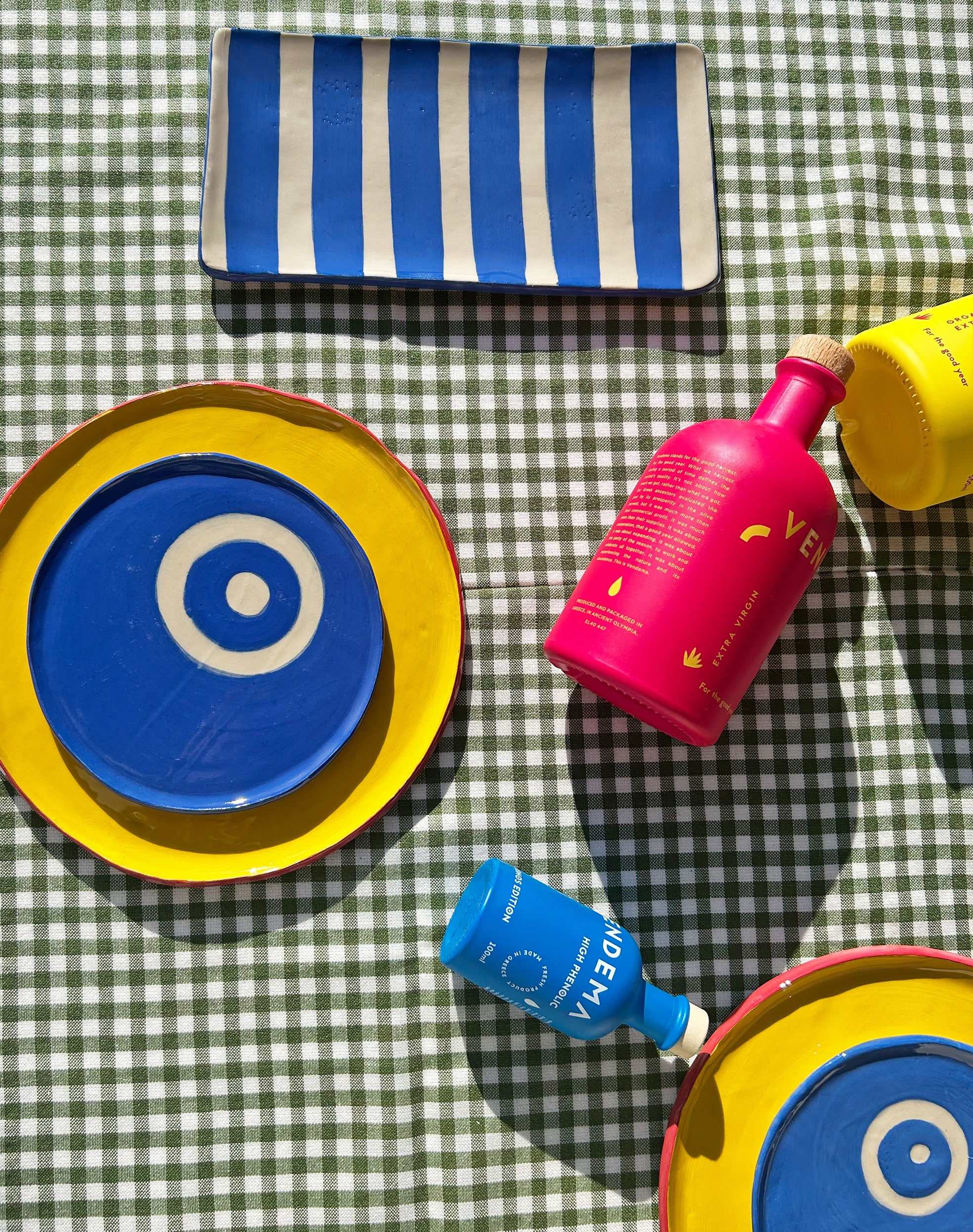 View from above of colourful ceramic plates and platters and Vendema Olive Oil Bottles.