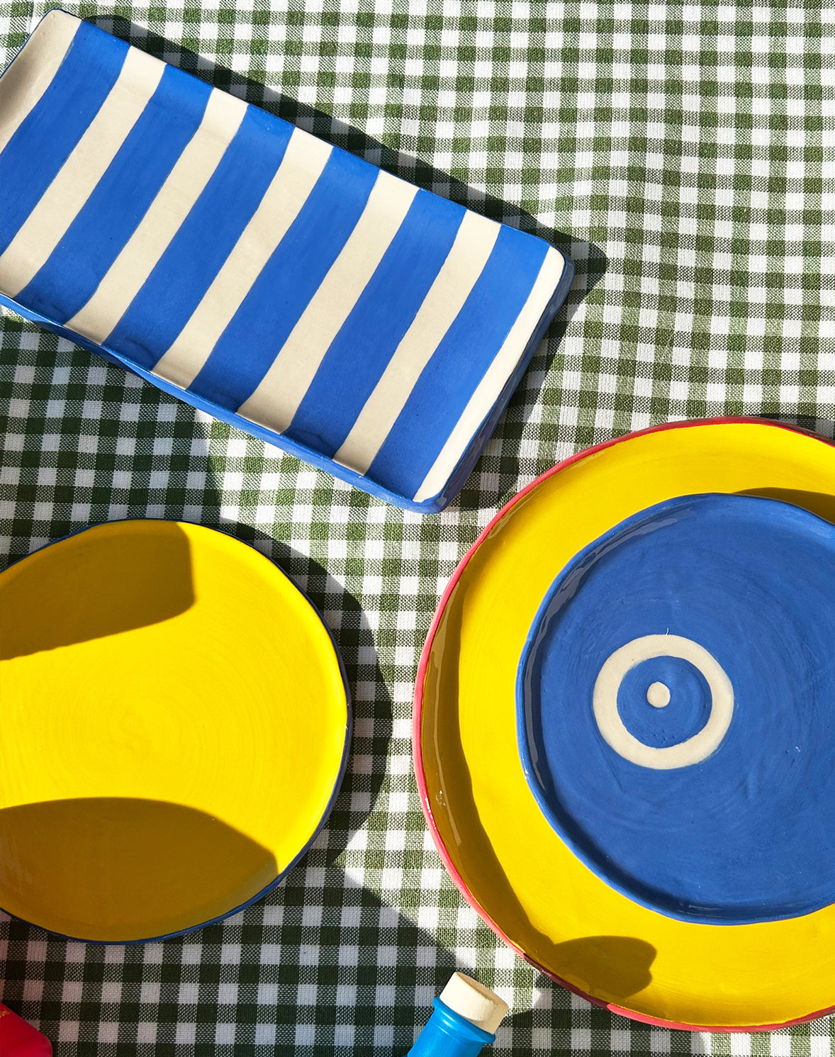 View from above of colourful ceramic plates and platters and Vendema Olive Oil Bottles.