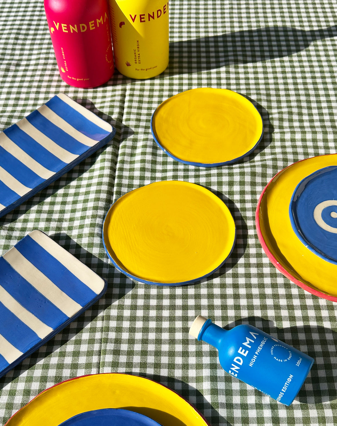 View from above of colourful ceramic plates and platters and Vendema Olive Oil Bottles.